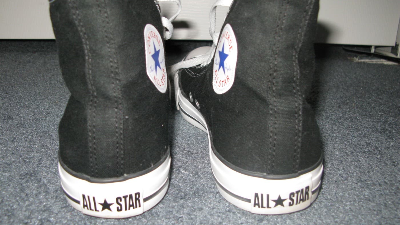 A pair of black Converse Chuck Taylor All Star sneakers, seen from behind. Illustrative photo, not the campaign image.
