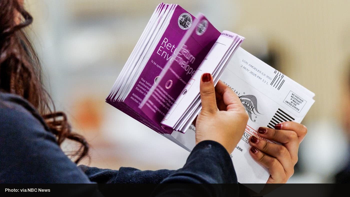 An election worker holds mail-in ballot return envelopes.