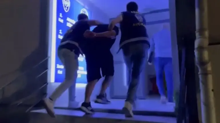 Police escorting a suspect into custody at night in Esenyurt, Istanbul