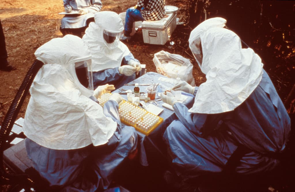 Scientists in full protective equipment processing samples during an Ebola outbreak response (file photo, CDC)