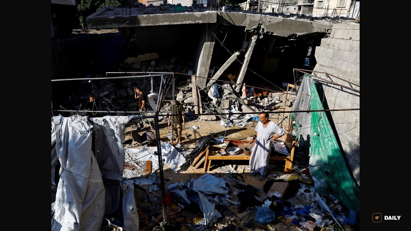 A displaced Palestinian man stands amid the rubble of a destroyed building next to a makeshift tent shelter in Gaza