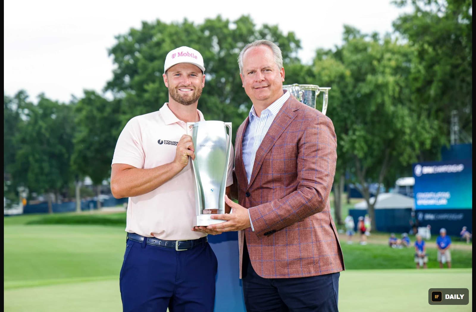Wyndham Clark holding the BMW Championship trophy alongside a BMW of North America executive on the golf course