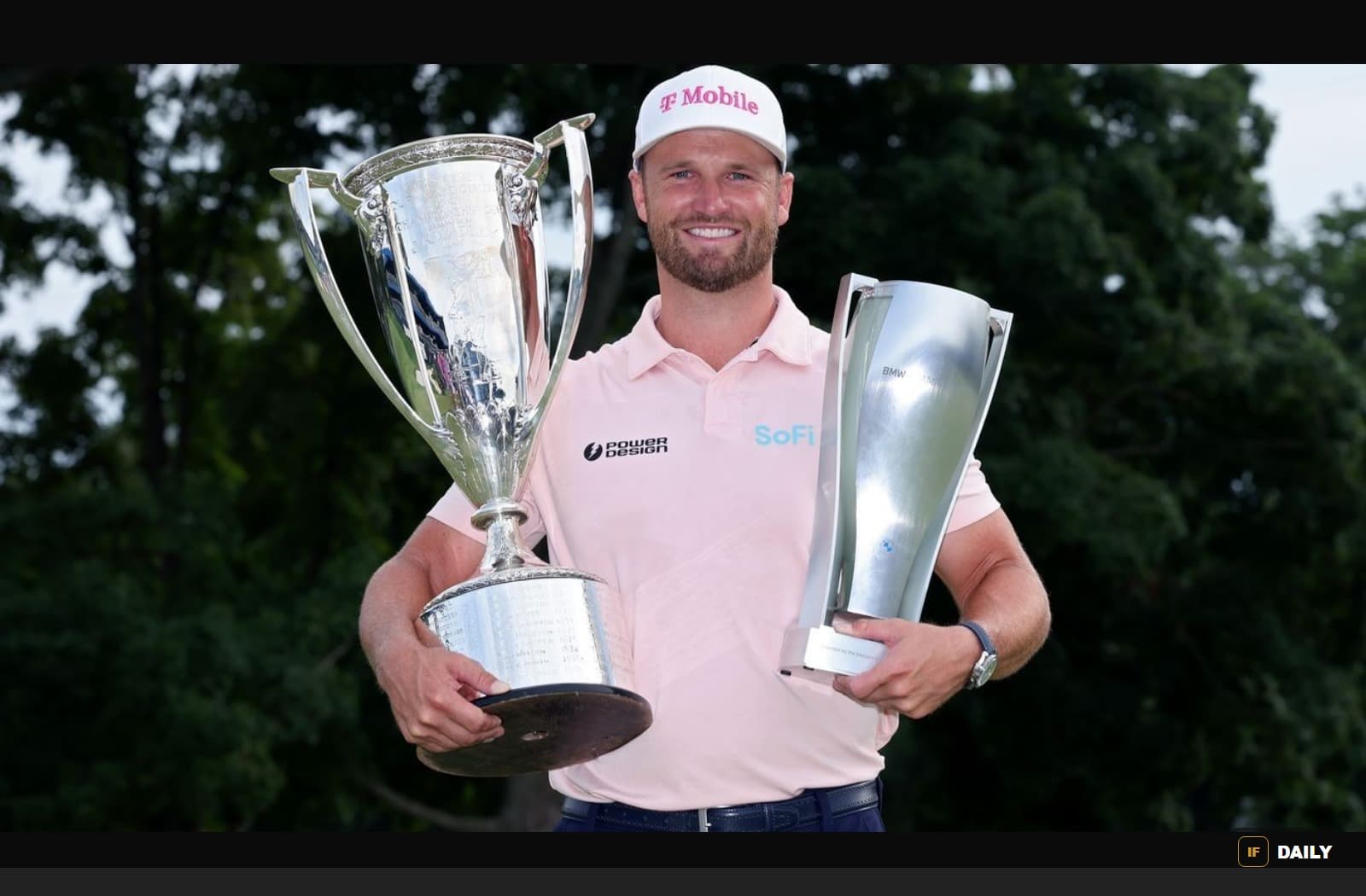 Wyndham Clark smiling and holding two golf trophies on the course