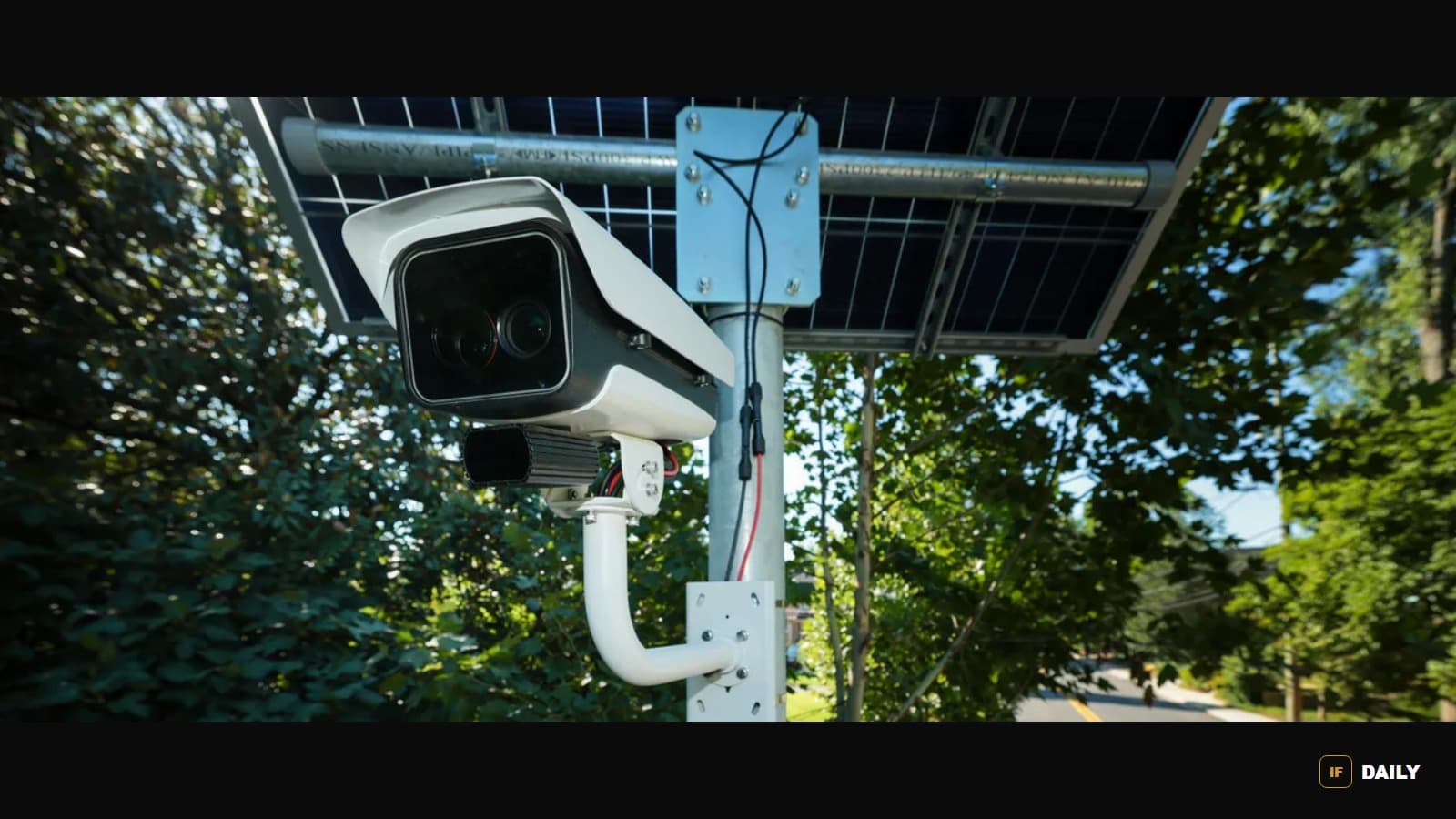 Close-up of a solar-powered Flock automated license plate reader camera mounted on a pole among trees
