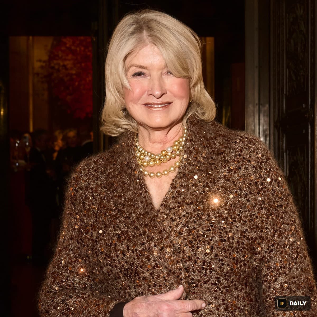 Martha Stewart smiling at an event wearing a sequined brown sweater and pearl necklace
