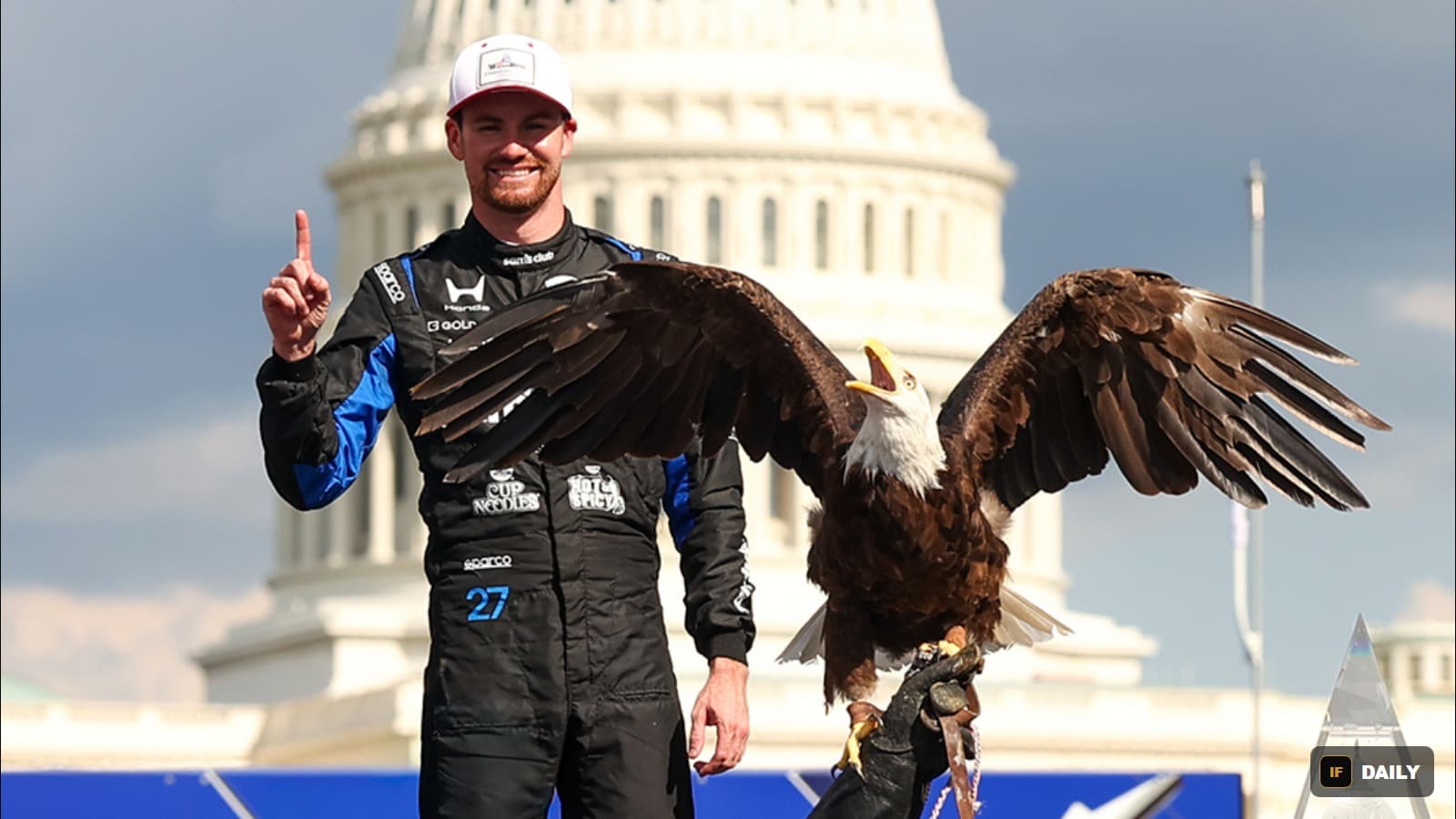 Kyle Kirkwood in his racing suit holding a bald eagle on his arm, with the US Capitol dome behind him