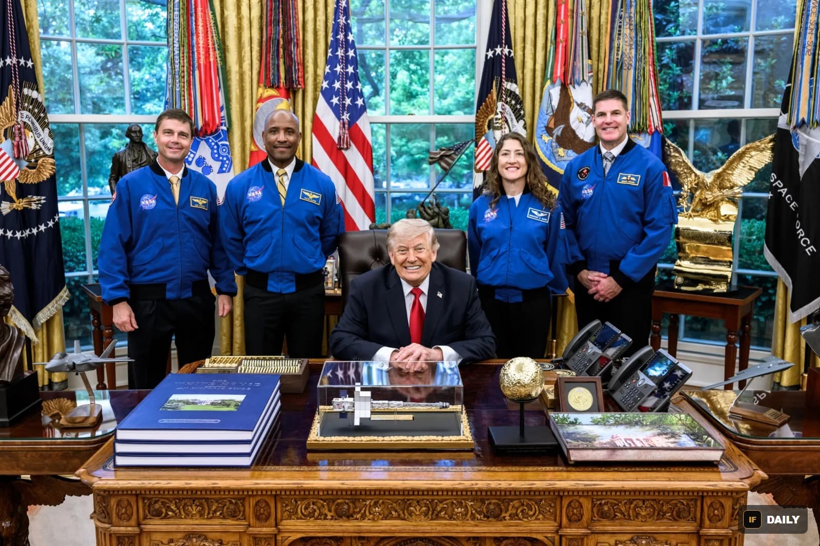The four Artemis II astronauts in blue NASA jackets standing with President Trump in the Oval Office
