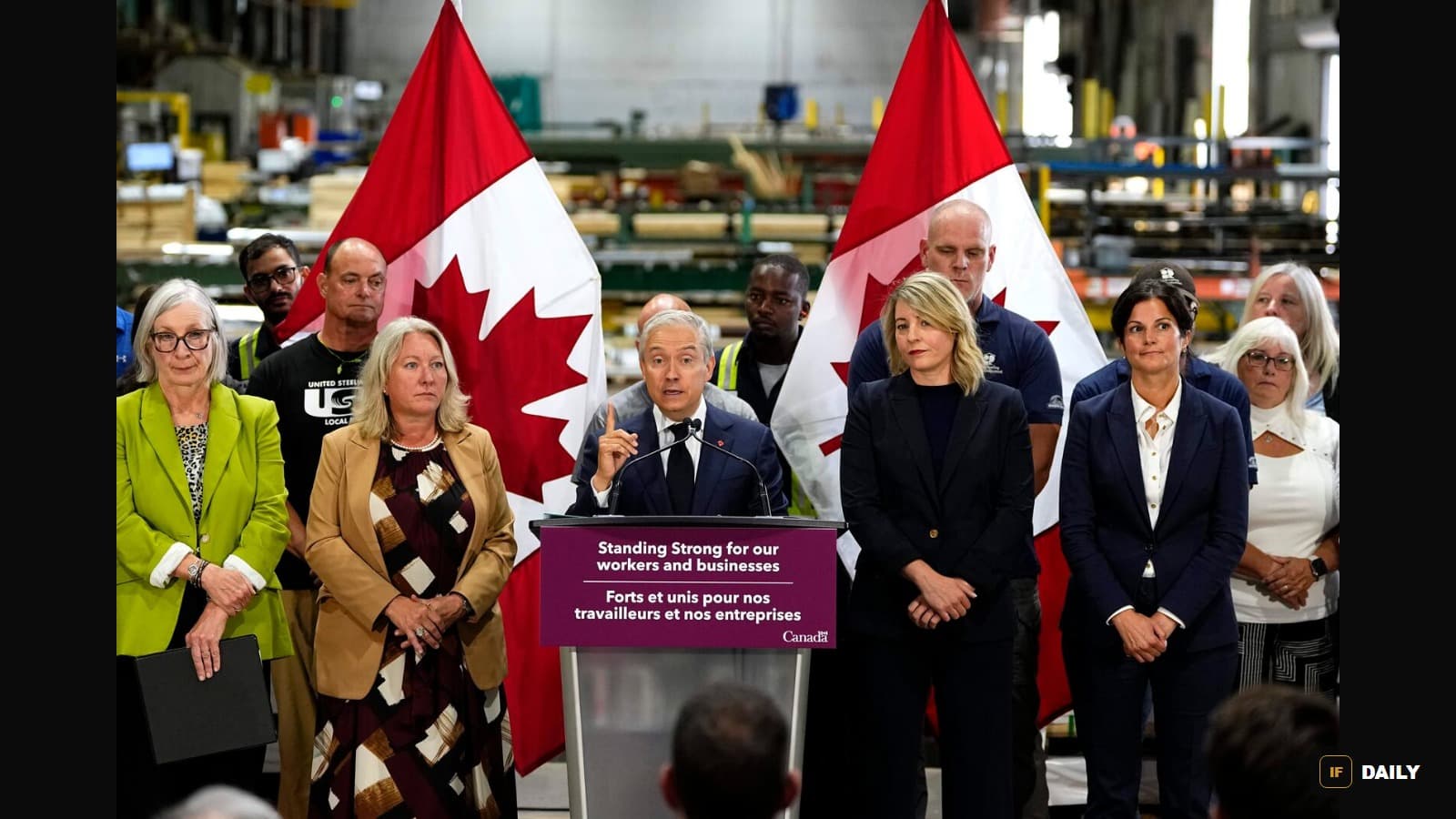 Canadian officials standing at a podium reading "Standing Strong for our workers and businesses" in front of Canadian flags at a manufacturing facility