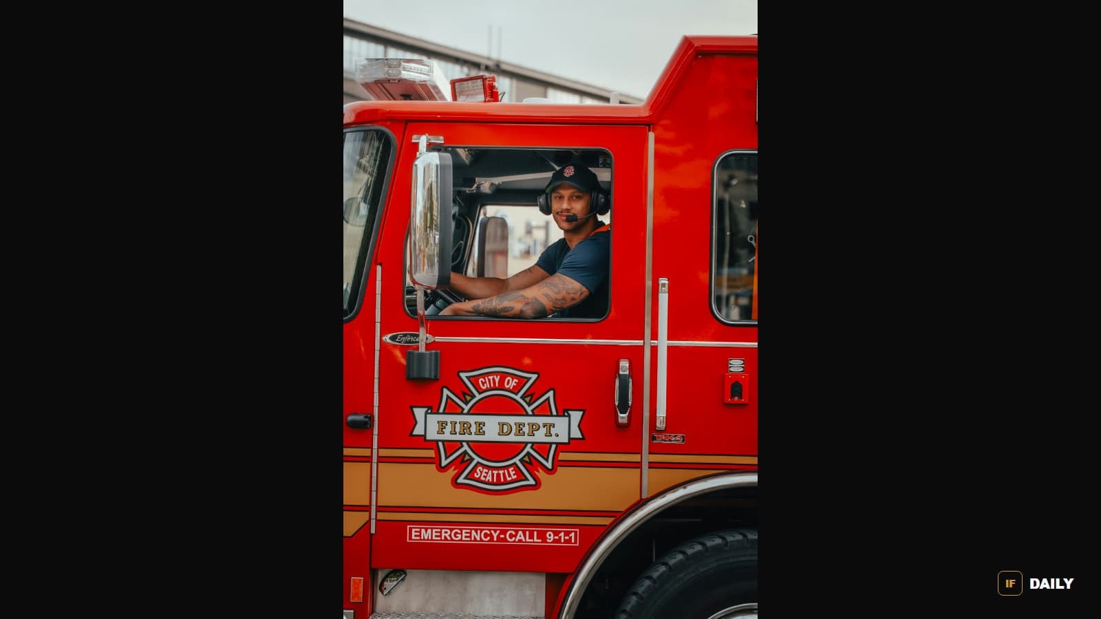 A firefighter sitting in the cab of a red fire engine marked City of Seattle Fire Dept
