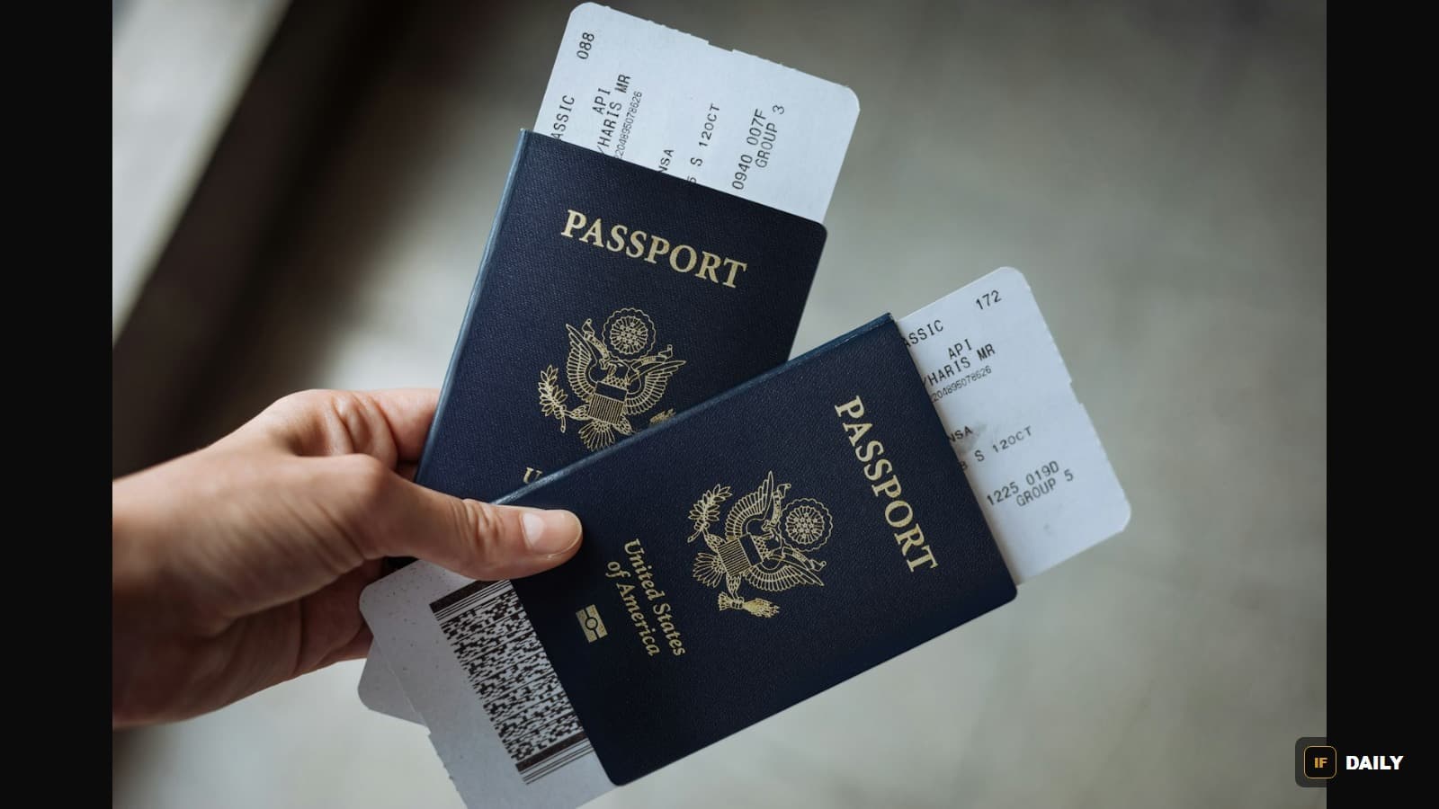 A hand holding two United States passports with airline boarding passes tucked inside the covers