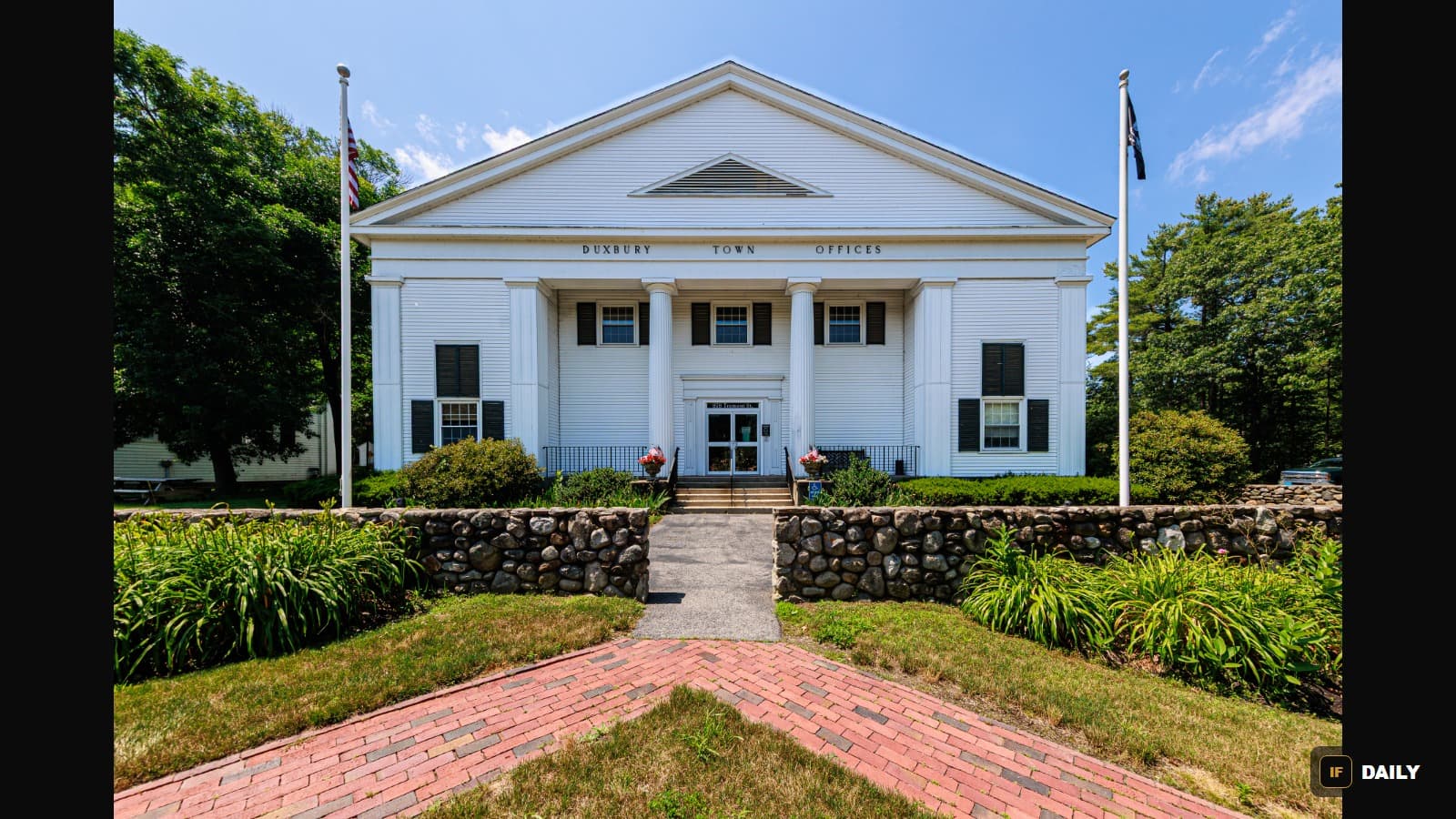 The white colonial-style Duxbury, Massachusetts Town Offices building with an American flag out front