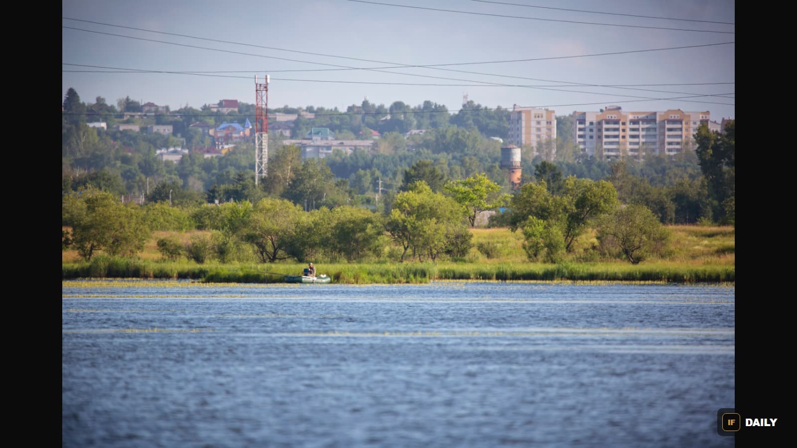 View of Svobodny, Amur Oblast, Russia, with apartment buildings and a water tower on the horizon beyond a river