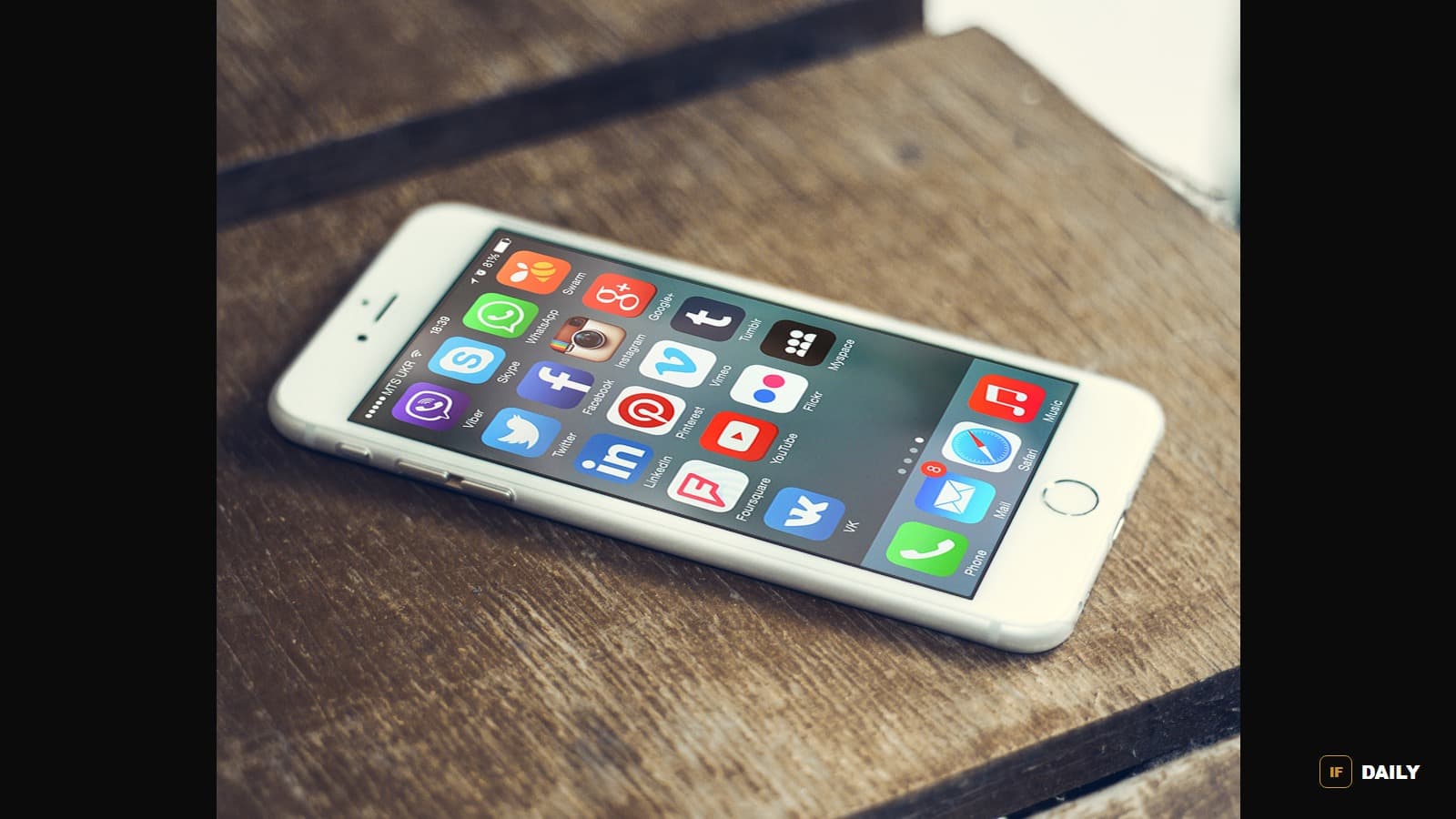 A smartphone displaying social media app icons on a wooden table