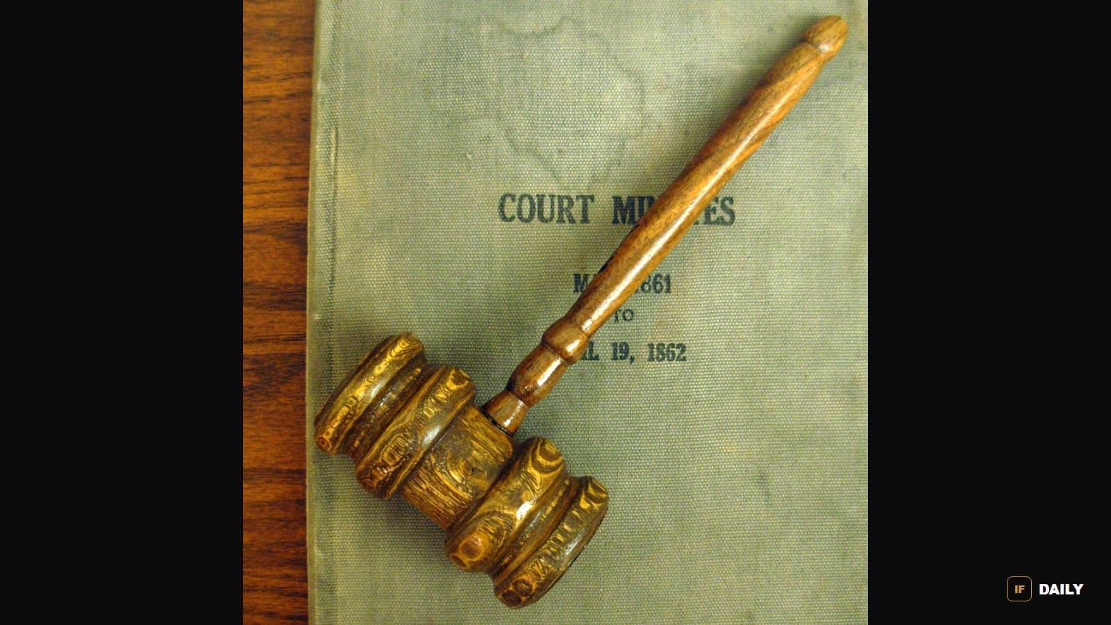 An old wooden courtroom gavel resting on a bound volume of court minutes