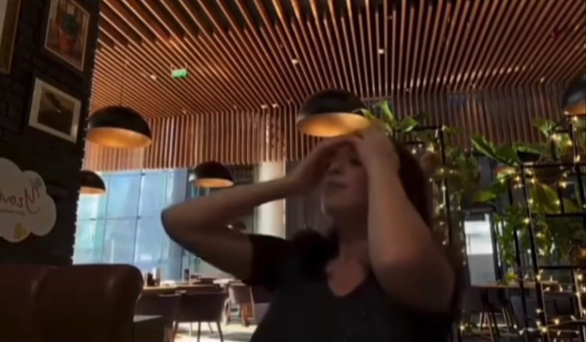 Blurred video from viral Threads post showing woman in restaurant during moment described as not playful