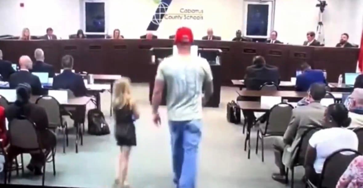 A father stands beside his young daughter while addressing the Cabarrus County Board of Education.